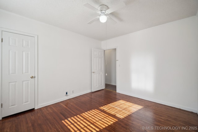 spare room with a textured ceiling, ceiling fan, and dark wood-type flooring