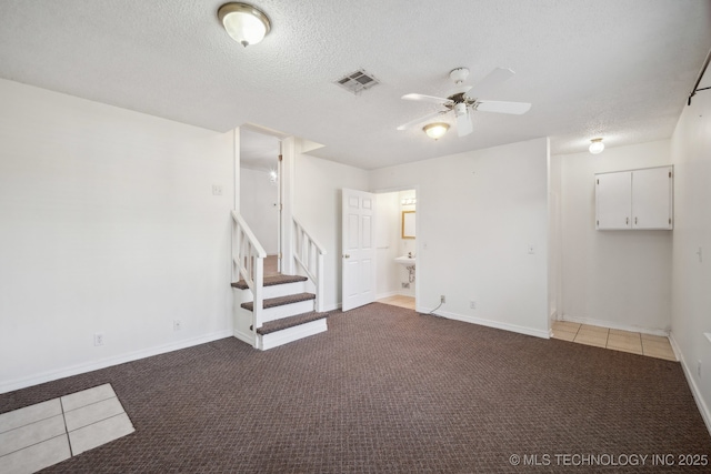 basement featuring ceiling fan, light colored carpet, and a textured ceiling