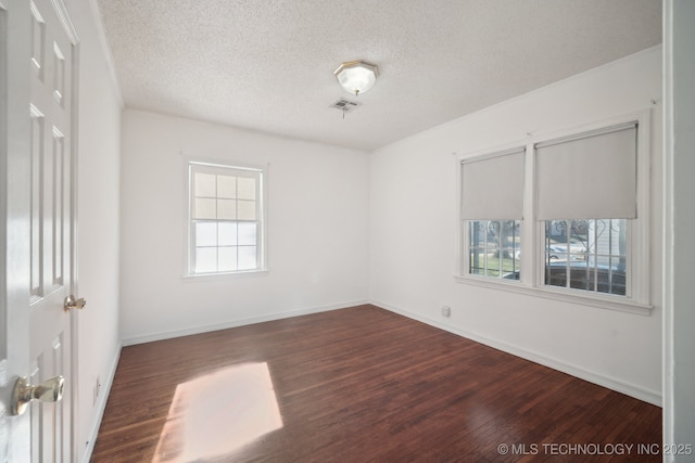 spare room featuring a textured ceiling and dark hardwood / wood-style flooring