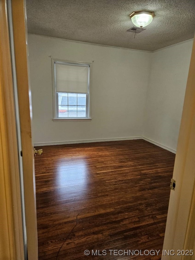 unfurnished room with a textured ceiling and dark hardwood / wood-style flooring