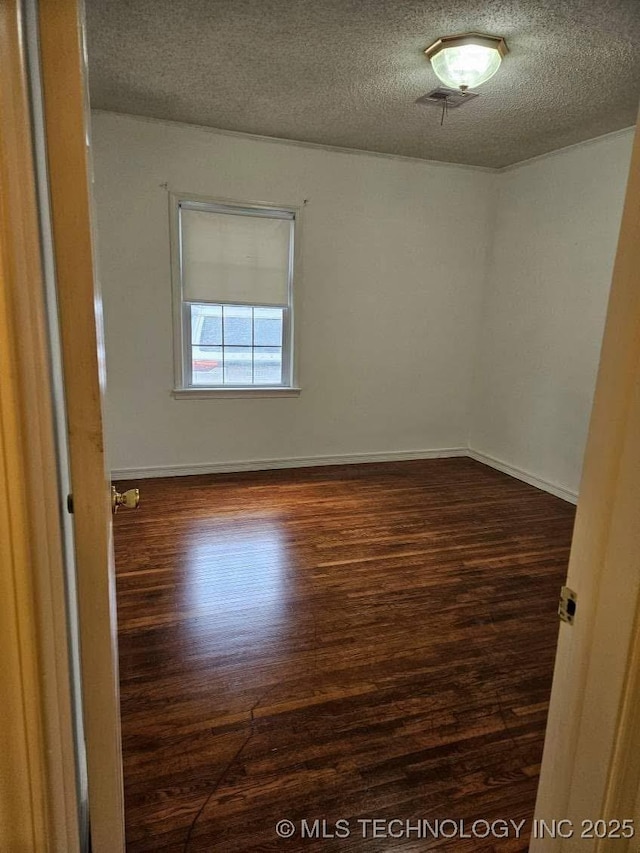 4519 E 5th Pl, Tulsa, OK 74112 - spare room with dark wood finished floors, a textured ceiling, and baseboards