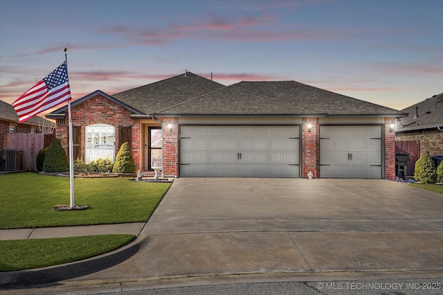 ranch-style home featuring central AC, a yard, and a garage