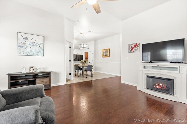 living room featuring ceiling fan, lofted ceiling, and dark wood-type flooring