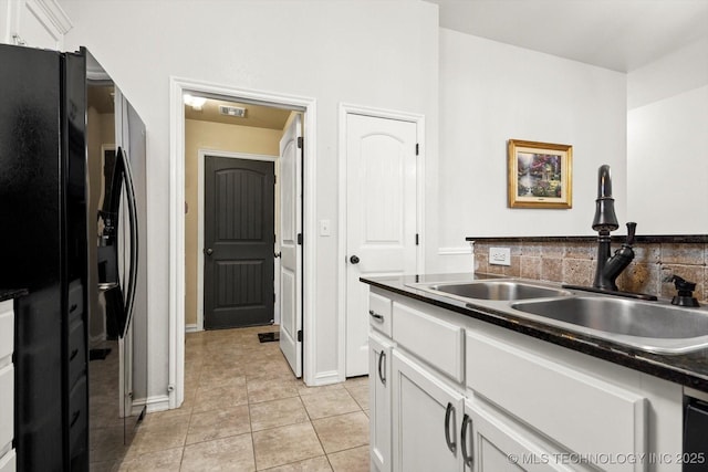 kitchen featuring black refrigerator with ice dispenser, sink, white cabinets, and light tile patterned flooring