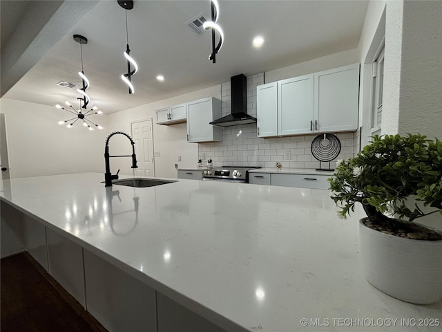 kitchen with white cabinets, sink, wall chimney exhaust hood, decorative backsplash, and decorative light fixtures