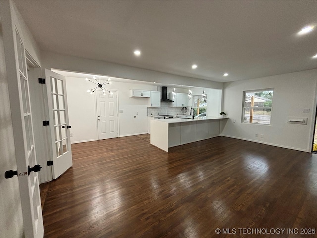 kitchen featuring kitchen peninsula, tasteful backsplash, an inviting chandelier, white cabinets, and dark hardwood / wood-style floors