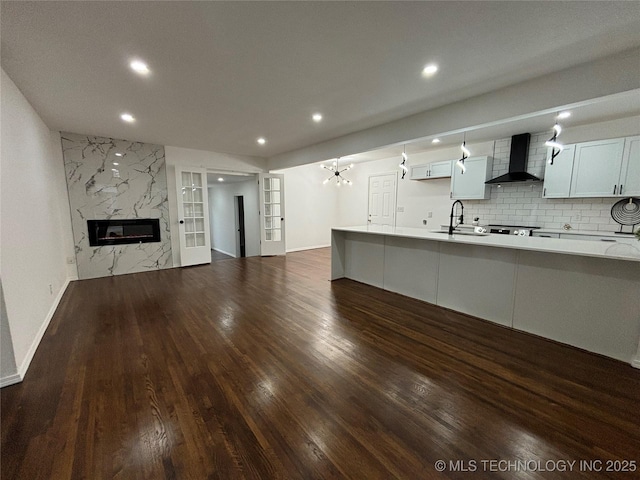 unfurnished living room with sink, french doors, an inviting chandelier, a high end fireplace, and dark hardwood / wood-style floors