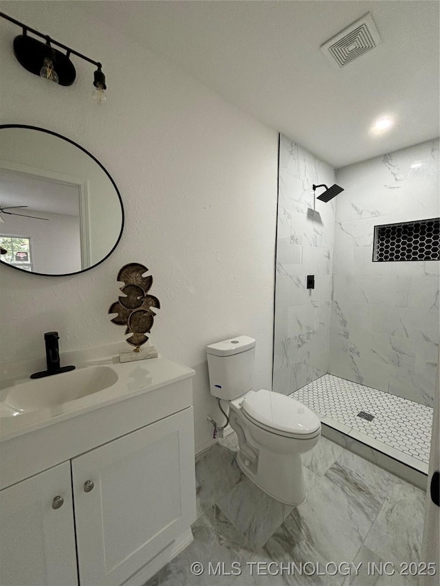 bathroom featuring a tile shower, ceiling fan, vanity, and toilet