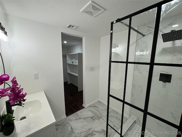 bathroom featuring vanity, a textured ceiling, and walk in shower