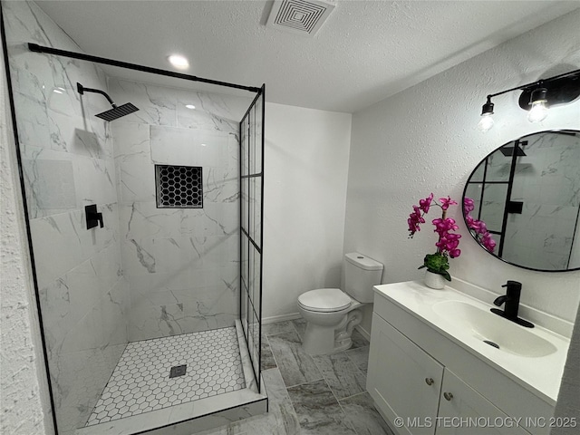 bathroom featuring vanity, a textured ceiling, tiled shower, and toilet