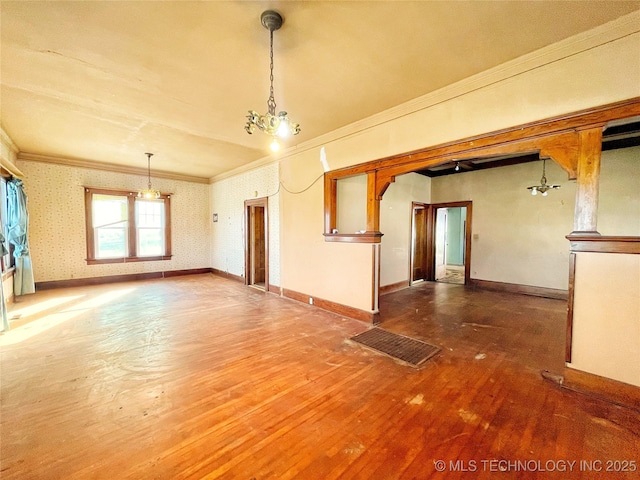 spare room featuring ornamental molding, hardwood / wood-style flooring, and a notable chandelier