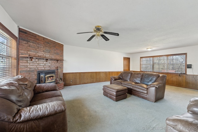 carpeted living room with a textured ceiling, a wood stove, ceiling fan, and wooden walls