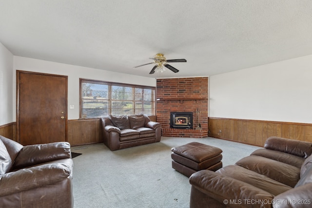 living room with a wood stove, wooden walls, ceiling fan, and light carpet