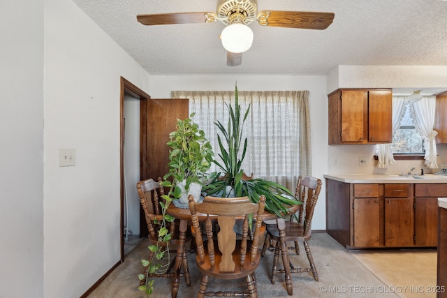 dining area with ceiling fan, sink, and a textured ceiling