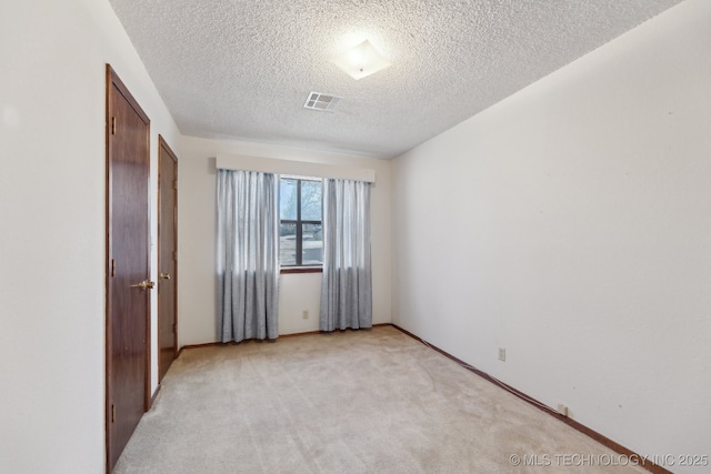 interior space featuring light colored carpet and a textured ceiling