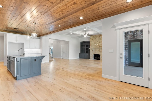 kitchen with white cabinetry, wooden ceiling, decorative light fixtures, a center island with sink, and light wood-type flooring