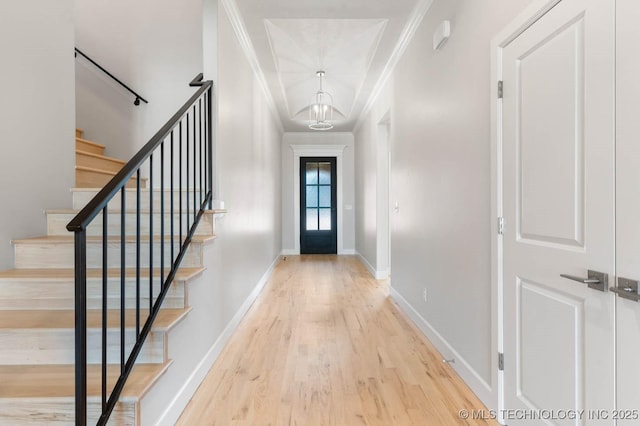 entryway featuring a chandelier, hardwood / wood-style flooring, and crown molding