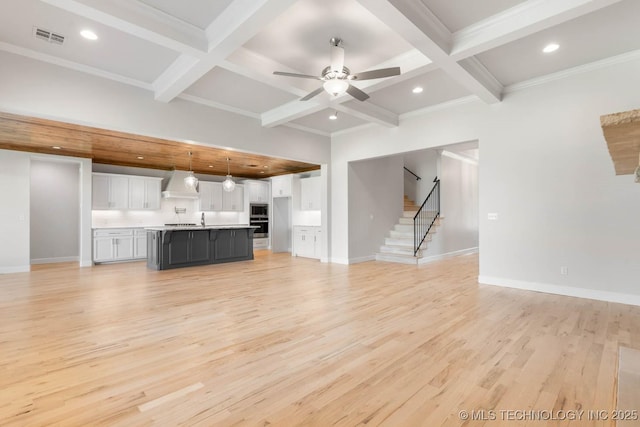 unfurnished living room featuring beamed ceiling, light wood-type flooring, and coffered ceiling