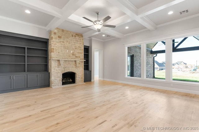 unfurnished living room with beamed ceiling, built in features, a stone fireplace, and coffered ceiling