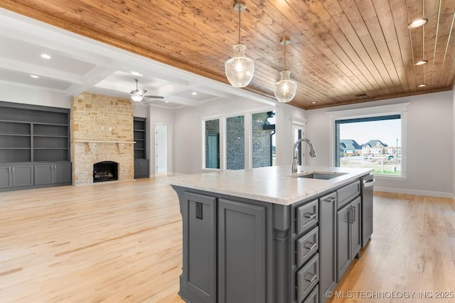 kitchen with sink, wooden ceiling, an island with sink, decorative light fixtures, and a fireplace