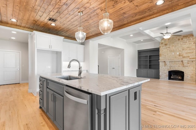 kitchen featuring built in shelves, white cabinetry, dishwasher, sink, and hanging light fixtures