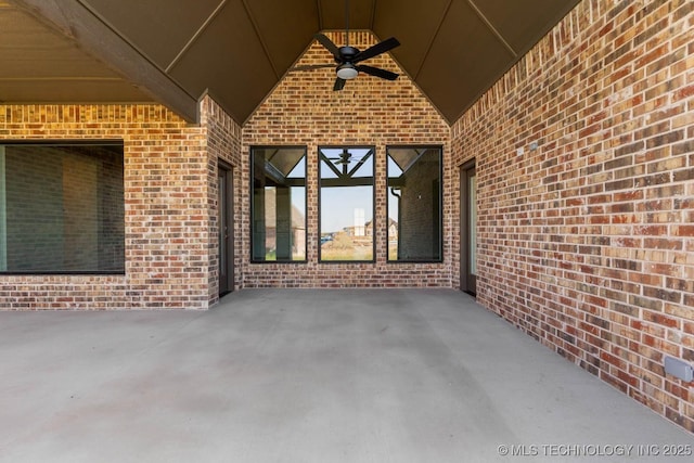 view of exterior entry with ceiling fan and a patio