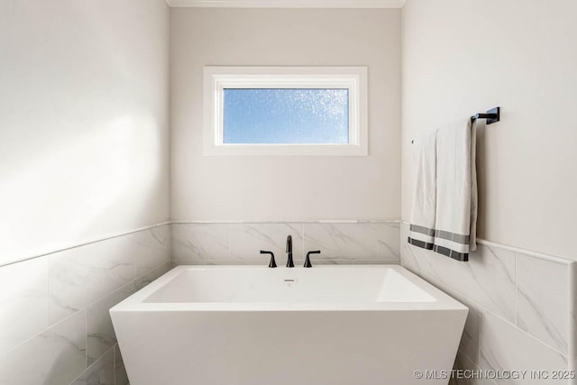 bathroom with a washtub and tile walls