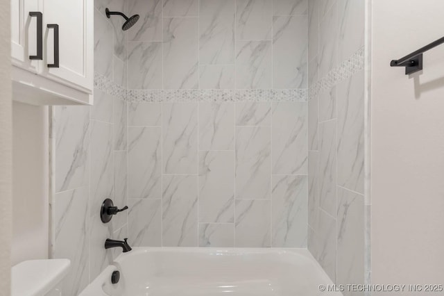 bathroom featuring tiled shower / bath and toilet