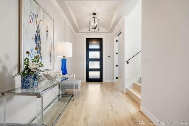 foyer entrance featuring light hardwood / wood-style floors, ornamental molding, and an inviting chandelier