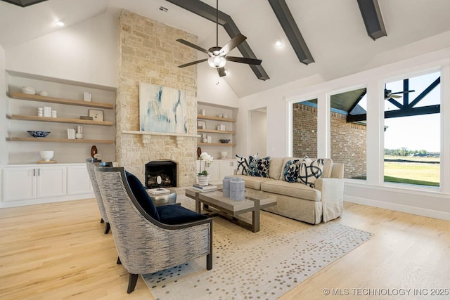 living room with beam ceiling, light wood-type flooring, built in features, and a fireplace