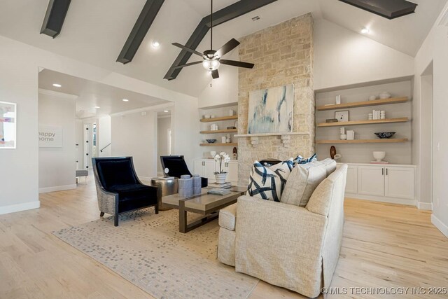 living room featuring built in shelves, ceiling fan, beam ceiling, light hardwood / wood-style flooring, and a fireplace