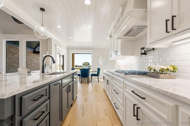 kitchen featuring light stone countertops, white cabinetry, pendant lighting, and custom exhaust hood