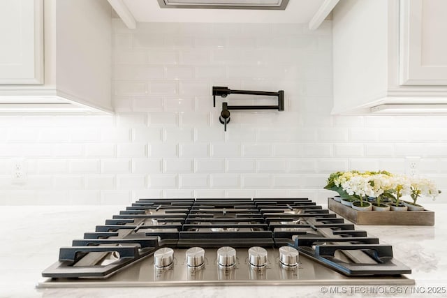 room details featuring light stone countertops, backsplash, white cabinetry, and stainless steel gas stovetop