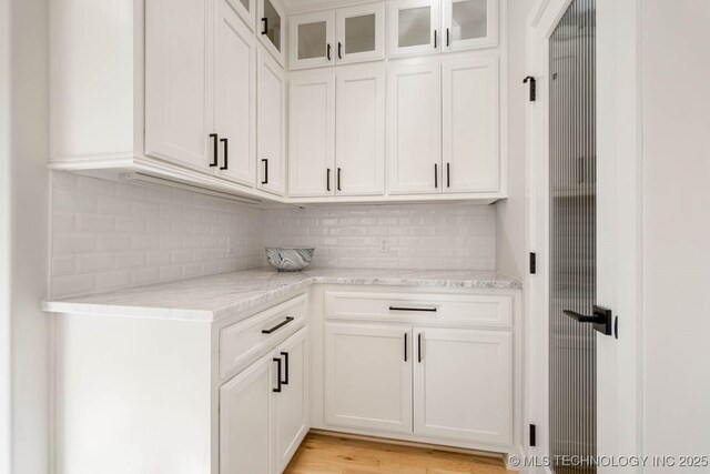 bar with white cabinets, tasteful backsplash, and light stone countertops