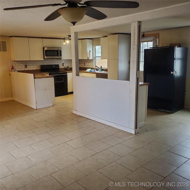 kitchen featuring tasteful backsplash, a healthy amount of sunlight, a textured ceiling, and black appliances