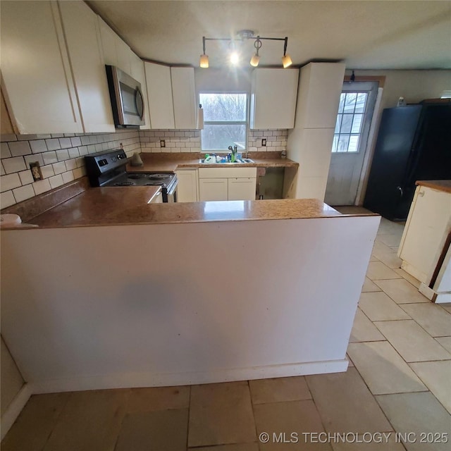 kitchen with tasteful backsplash, white cabinets, kitchen peninsula, stainless steel appliances, and a healthy amount of sunlight