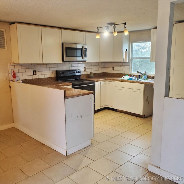 kitchen with light tile patterned floors, a textured ceiling, range with electric cooktop, and white cabinets