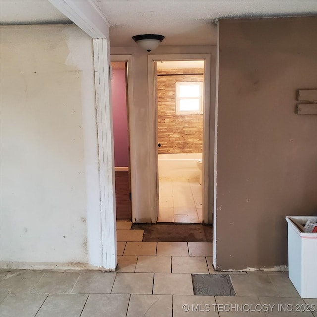 corridor with light tile patterned flooring and a textured ceiling