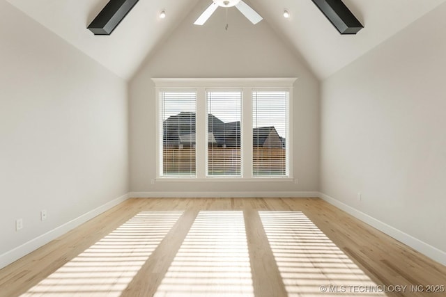 spare room featuring baseboards, a ceiling fan, light wood-style flooring, and lofted ceiling