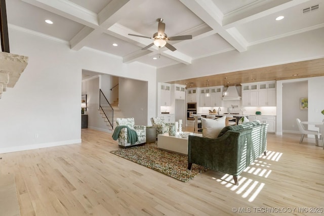 living area with stairway, light wood-style floors, coffered ceiling, and visible vents