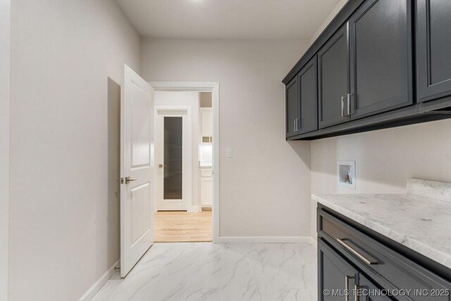 washroom with cabinet space, washer hookup, baseboards, and marble finish floor