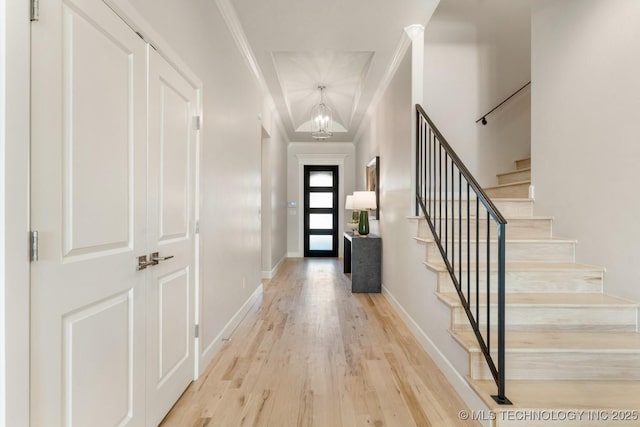entrance foyer featuring baseboards, a notable chandelier, light wood-style floors, ornamental molding, and stairs