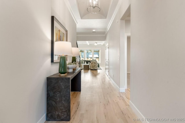 hallway featuring crown molding, baseboards, an inviting chandelier, and light wood-type flooring