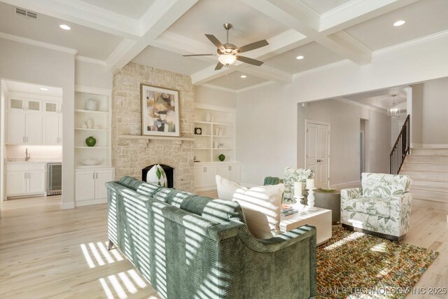 living area featuring beverage cooler, light wood finished floors, beam ceiling, and visible vents
