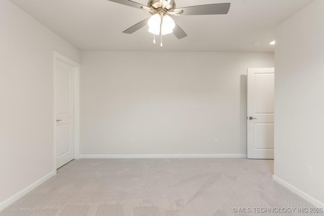 spare room featuring light colored carpet, baseboards, and ceiling fan