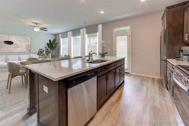 kitchen with sink, an island with sink, light hardwood / wood-style flooring, and appliances with stainless steel finishes