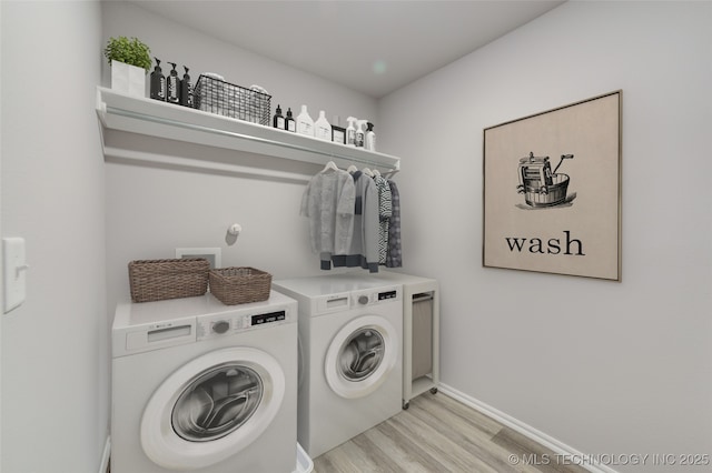 clothes washing area with washer and dryer and light hardwood / wood-style flooring