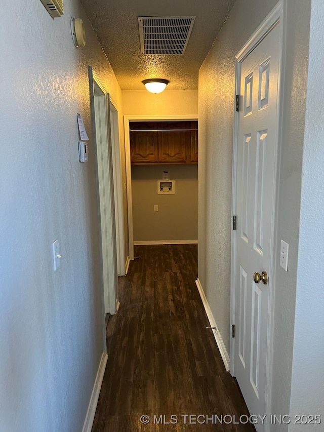 hall with a textured ceiling and dark wood-type flooring