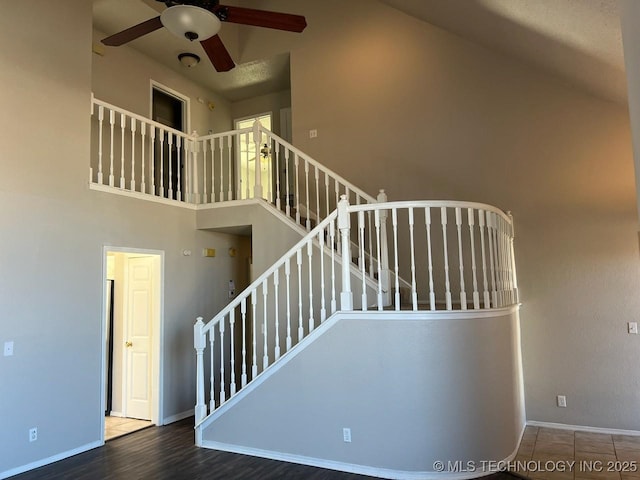 stairs with ceiling fan, hardwood / wood-style floors, and a towering ceiling