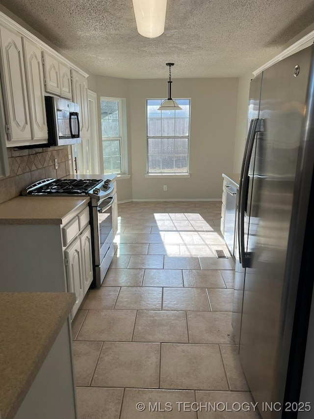 kitchen with backsplash, a textured ceiling, stainless steel appliances, decorative light fixtures, and white cabinets